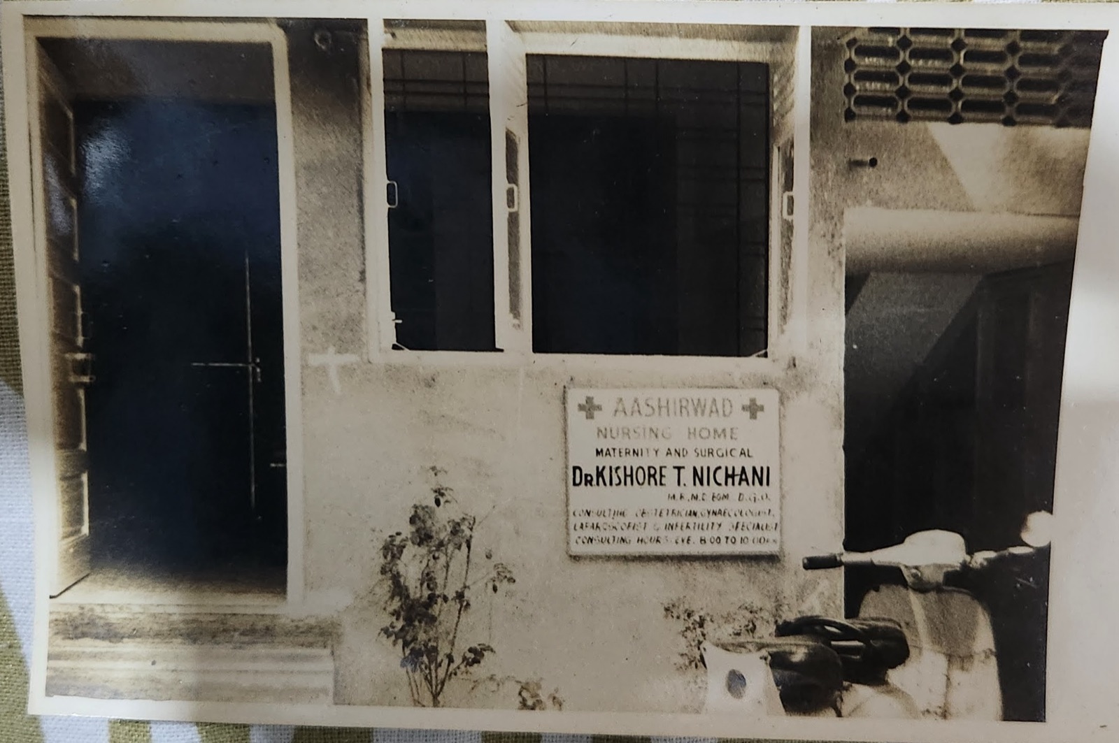 Archival black and white photograph of the original Aashirwad Nursing Home board — Maternity and Surgical, Dr. Kishore T. Nichani